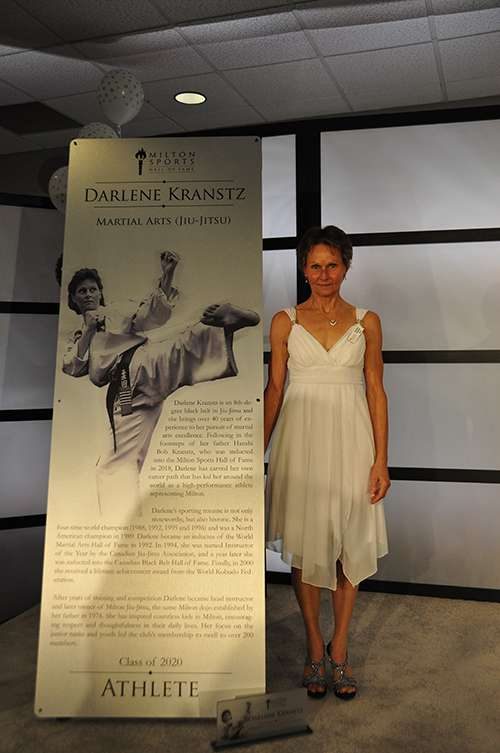 Darlene Kranstz beside her Milton Sports Hall of Fame banner